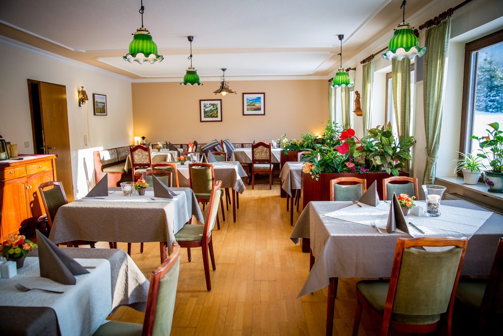 Frühstücksraum mit gedeckten Tischen und grünen Pendelleuchten