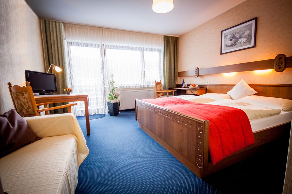 Doppelzimmer mit Holzbett, Bild an der Wand und Fernseher